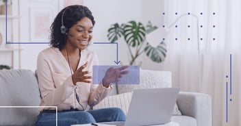 person speaking with a headset on using her laptop at home