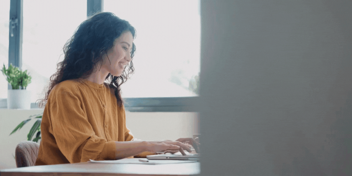 Call center agent sitting at a computer with icons of applications pointing towards a computer screen to showcase a unified agent desktop