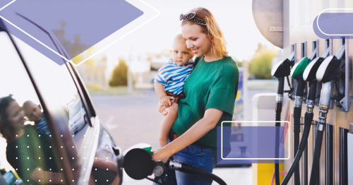 mom holding baby while filling her car with gas at a gas station